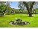 Landscaped backyard featuring a stone picnic table, gazebo, pond and mature trees at 1007 Lakewood Dr, Brandon, FL 33510