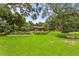 Expansive backyard with lush green lawn, mature trees, and screened patio at 1007 Lakewood Dr, Brandon, FL 33510