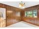 Charming dining area featuring wood paneling, large window with natural light, and an elegant chandelier at 1007 Lakewood Dr, Brandon, FL 33510