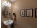 Cozy powder room with pedestal sink, decorative mirror, and framed art prints at 10120 Post Harvest Dr, Riverview, FL 33578