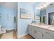 Charming blue bathroom with a wide vanity, quartz countertop, golden hardware and a tiled walk-in shower at 10532 94Th Pl, Seminole, FL 33772