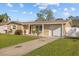 Tan house with white garage door, landscaping, and a paved driveway at 1418 Barry St, Clearwater, FL 33756