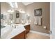 Bathroom with double sinks, framed mirrors, wood cabinets and hard wood floor at 14607 Turning Leaf Ct, Tampa, FL 33626