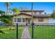 Tan two-story house with a black fence, brick pathway, and lush lawn at 156 29Th N Ave, St Petersburg, FL 33704