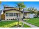 Tan two-story house with a brick pathway, lush lawn, and palm trees at 156 29Th N Ave, St Petersburg, FL 33704