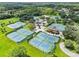 Aerial view of multiple tennis courts and community building surrounded by greenery at 16908 Equestrian Trl, Odessa, FL 33556