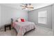 Neutral bedroom with window includes bed, side table, ceiling fan and gray carpeting at 16908 Equestrian Trl, Odessa, FL 33556