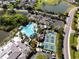 Aerial view of a large community pool and tennis courts surrounded by palm trees and lush landscaping at 1901 Andover Way # 32, Sun City Center, FL 33573