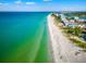 Aerial view of the community's beach, clear blue ocean, white sand, and stunning waterfront properties at 192 Haven Beach Dr, Indian Rocks Beach, FL 33785