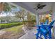 Charming covered patio with blue Adirondack chairs overlooking the lush backyard and waterfront at 192 Haven Beach Dr, Indian Rocks Beach, FL 33785