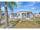 Single-story home featuring a covered porch, large palm trees, and lush landscaping at 206 S Port Royal Ln, Apollo Beach, FL 33572