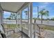 Enclosed lanai with a view of palm trees and a white fence. The lanai has chairs, a wood deck and screening at 206 S Port Royal Ln, Apollo Beach, FL 33572