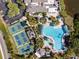 Aerial view showcasing a pool, tennis courts, and clubhouse, embraced by lush landscaping and clear skies at 2471 Kensington Greens Dr, Sun City Center, FL 33573