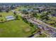 Scenic aerial view of community entrance with immaculate lawns, mature trees, landscaping, and a glimpse of a serene pond at 2471 Kensington Greens Dr, Sun City Center, FL 33573