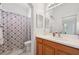 Bright bathroom with a wooden vanity and a shower tub combination with a patterned curtain at 2471 Kensington Greens Dr, Sun City Center, FL 33573