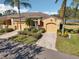 Lovely home with yellow exterior, two-car garage, paved driveway and tropical landscaping, near the lake at 2471 Kensington Greens Dr, Sun City Center, FL 33573