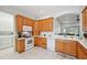 Bright kitchen featuring oak cabinets, white appliances, and an open layout to the living area at 2471 Kensington Greens Dr, Sun City Center, FL 33573