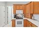 A compact kitchen area featuring oak cabinets, white appliances, and efficient countertop space at 2471 Kensington Greens Dr, Sun City Center, FL 33573