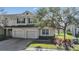 Charming two-story townhome with a brick driveway, manicured lawn, and view of a serene pond at 26850 Juniper Bay Dr, Wesley Chapel, FL 33544