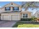 Two-story townhome showcasing neutral stucco, brick driveway, two-car garage, and manicured bushes at 26850 Juniper Bay Dr, Wesley Chapel, FL 33544