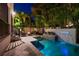 Resort-style pool with stone waterfall feature, lush landscaping, and exterior lighting perfect for evening enjoyment at 2810 W Alline Ave, Tampa, FL 33611