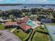 Aerial view of the clubhouse featuring a pool, tennis court, and a tranquil pond at 301 Mariner Dr # 301, Tarpon Springs, FL 34689