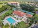 Aerial view of the community pool, with lounge chairs, manicured landscaping, and tennis courts at 301 Mariner Dr # 301, Tarpon Springs, FL 34689