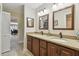 Well-lit bathroom with a double granite vanity, wooden cabinets, large mirrors, and views to other rooms at 315 Linger Ln, Sun City Center, FL 33573