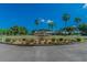 A beautifully landscaped entrance to Caloosa Country Club, with palm trees and vibrant flowers at 315 Linger Ln, Sun City Center, FL 33573