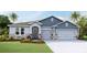 Two-story home with blue and gray siding, stone accents, and a three-car garage at 3426 Hazel Hollow Way, Plant City, FL 33565