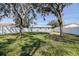 Wide backyard view featuring mature trees, and a well-maintained lawn enclosed by a white fence at 4570 69Th N Ave, Pinellas Park, FL 33781