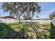 Backyard featuring mature trees, lush grass, a concrete patio, and a well-maintained white fence at 4570 69Th N Ave, Pinellas Park, FL 33781