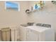 Functional laundry room featuring a washer, dryer, and shelving for convenient organization of laundry essentials at 4576 Garofalo Rd, Wesley Chapel, FL 33543