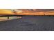 Calm beach at sunset with a sand design in the foreground, rocky breakwater, and distant figures enjoying the view at 505 67Th Ave # 5, St Pete Beach, FL 33706