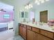 Bathroom with double sinks, wood cabinets, and a view into the Primary bedroom at 6467 Willowshire Way, Bradenton, FL 34212