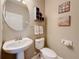 Elegant powder room featuring a pedestal sink, round mirror, and tasteful decor at 6467 Willowshire Way, Bradenton, FL 34212