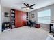 This bedroom features a built-in bookcase, ceiling fan, and a desk next to a window overlooking the neighborhood at 6467 Willowshire Way, Bradenton, FL 34212