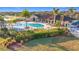 Stunning aerial image of the community clubhouse and a freeform pool with ample seating under blue umbrellas at 6467 Willowshire Way, Bradenton, FL 34212