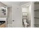 Neutral colored bathroom featuring tiled shower, glass shelving and toilet at 684 Bayway Blvd, Clearwater, FL 33767