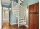 Bright white spiral staircase with wood flooring, next to wood storage cabinet at 684 Bayway Blvd, Clearwater, FL 33767