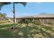 Rear exterior view of home featuring a well-manicured lawn, mature trees, and screened patio at 7161 Fairway Bend Cir, Sarasota, FL 34243