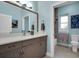 Well-lit bathroom featuring a modern vanity, decorative mirror, and a glimpse of a tiled shower area at 868 Date Palm Ln, St Petersburg, FL 33707