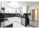 Modern kitchen with sleek white cabinetry, black countertops, and stainless steel refrigerator at 8807 Oak Cir, Tampa, FL 33615