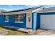 Charming single-story blue home features an attached garage, solar panels, and a well-manicured lawn at 8903 Bay Bridge Ct, Tampa, FL 33634