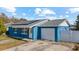 Charming single-story blue home features an attached garage, solar panels, and a well-manicured lawn at 8903 Bay Bridge Ct, Tampa, FL 33634