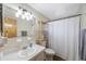 Bright bathroom with a large mirror, white shower curtain, and convenient shelving unit at 10201 127Th Pl, Largo, FL 33773
