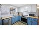 Well-lit kitchen with blue and white cabinetry, stainless steel appliances, and modern finishes at 10201 127Th Pl, Largo, FL 33773