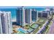 An aerial view of luxury beachfront condos featuring multiple pools, tennis courts, and manicured landscaping near the ocean at 1540 Gulf Blvd # 1705, Clearwater, FL 33767