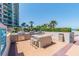 Outdoor kitchen with stainless steel grills, countertop island, and seating overlooking palm trees at 1540 Gulf Blvd # 1705, Clearwater, FL 33767
