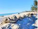 Beautiful beachfront with white sand, clear blue water, and scattered rocks near tropical foliage at 308 2Nd St N # 202, Bradenton Beach, FL 34217